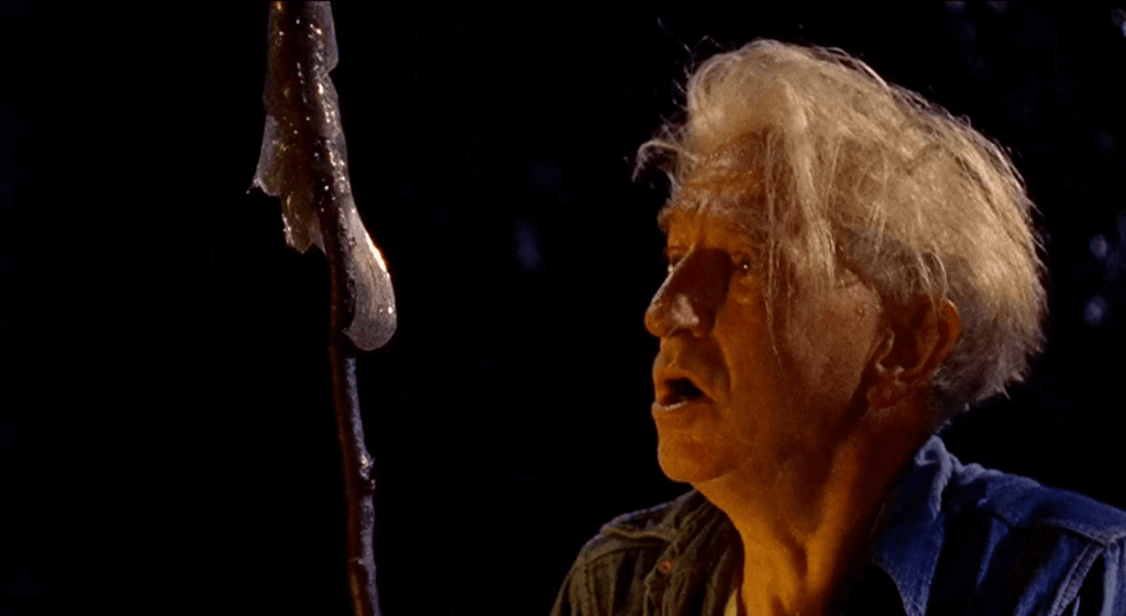 An elderly White man stares in horror at a large mucus-like substance on a stick.