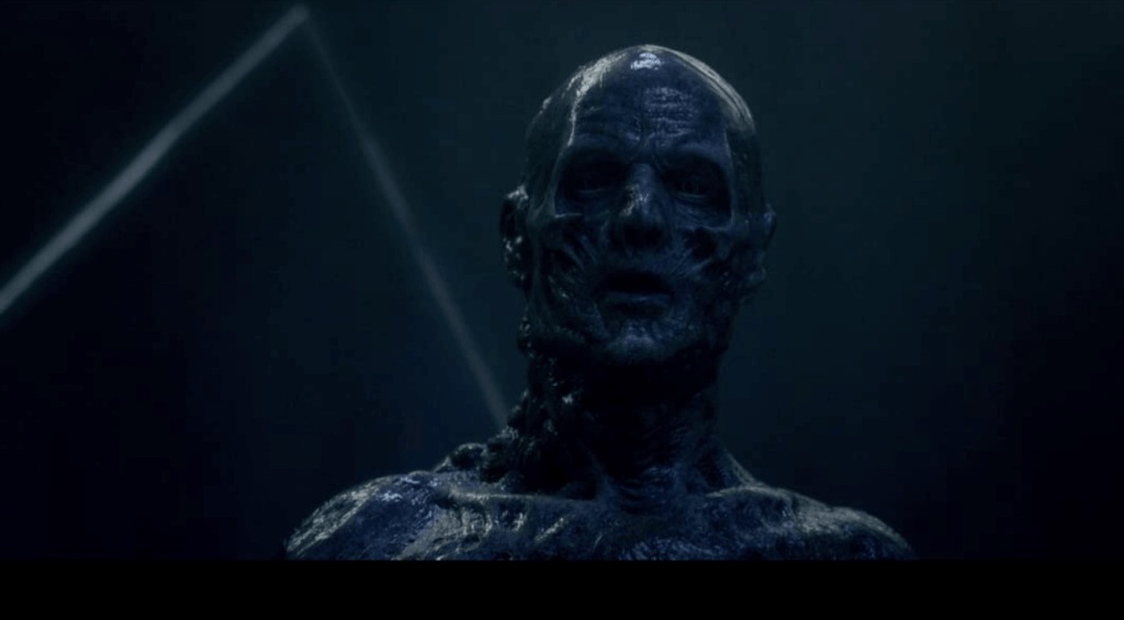 A male creature with human attributes. Dark gray skin, pitch black eyes, and sunken facial features.