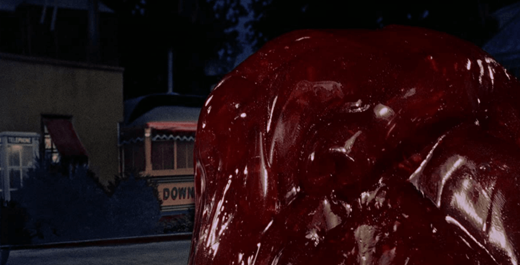 A giant red blob slithers down the street of a small town.