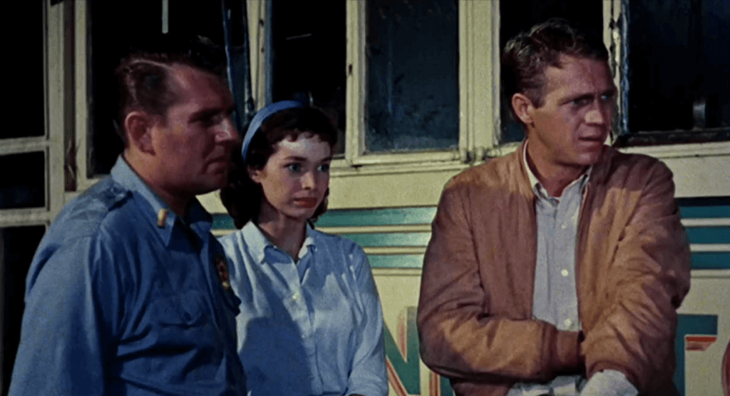 Steven McQueen looks worried next to a young woman and a male police officer. 