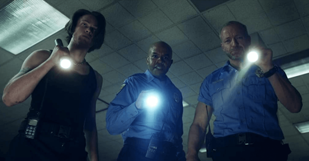 Three security guards staring with flashlights pointed from a first-person point of view.